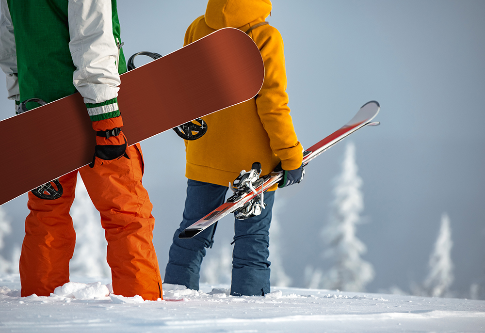 Two people holding skis and snowboard on snowy hilltop Halstead Haverhill apartments